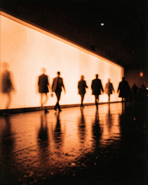 Des silhouettes floues devant un mur de lumière